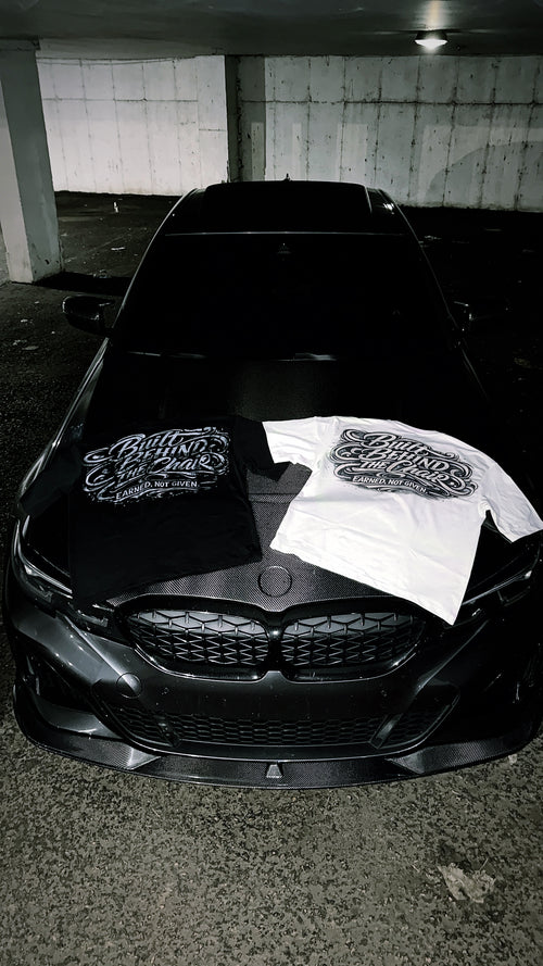 Black and white Built Behind the Chair graphic T-shirts displayed together on a car hood