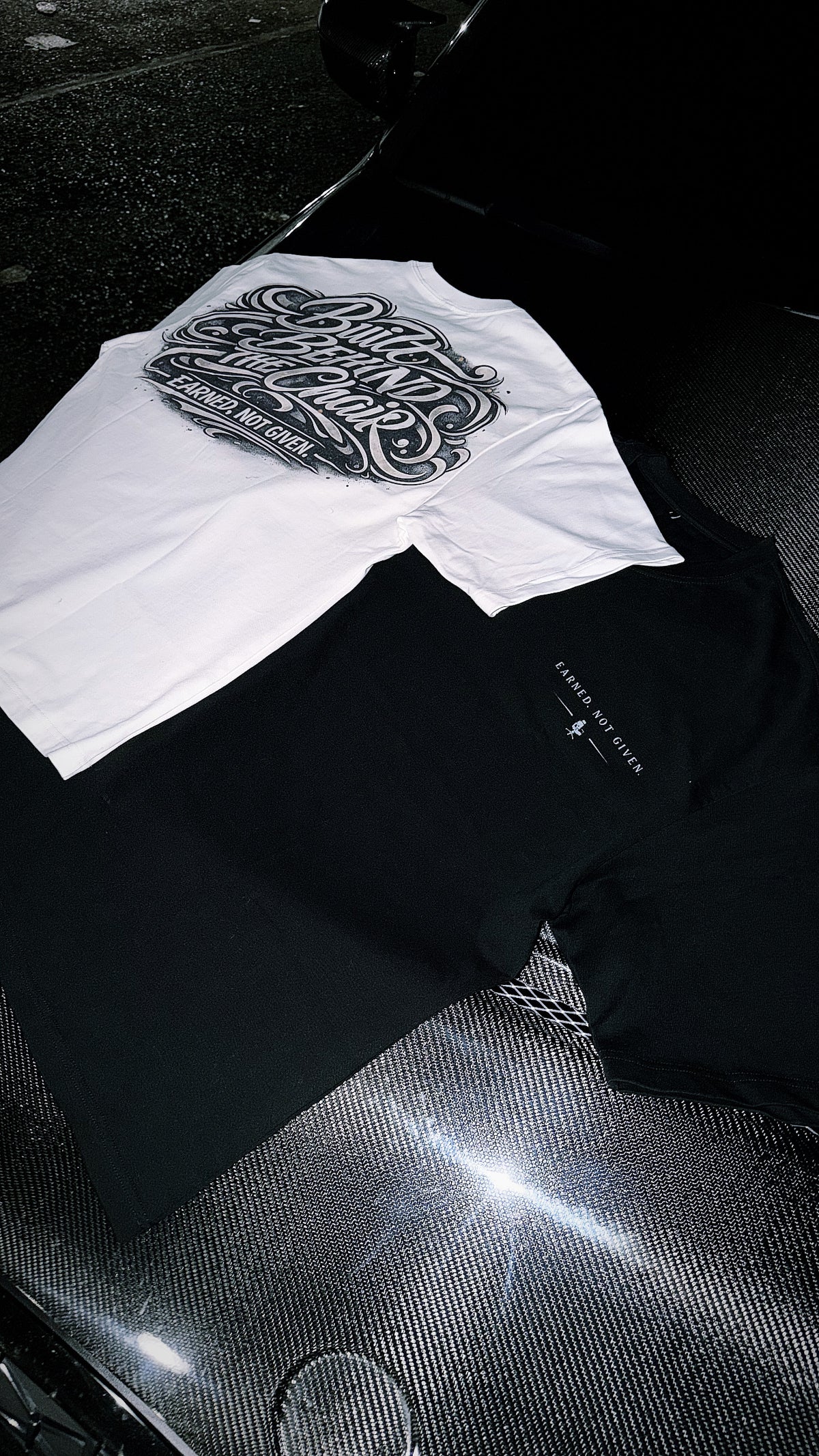 White graphic T-shirt with bold black lettering displayed alongside a black shirt